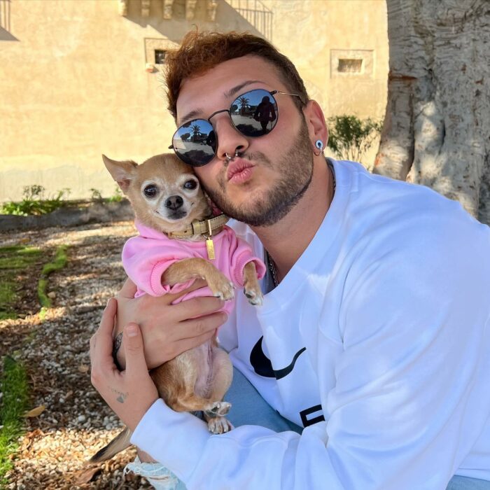 Fotografía de un joven cargando a su perro chihuahua 