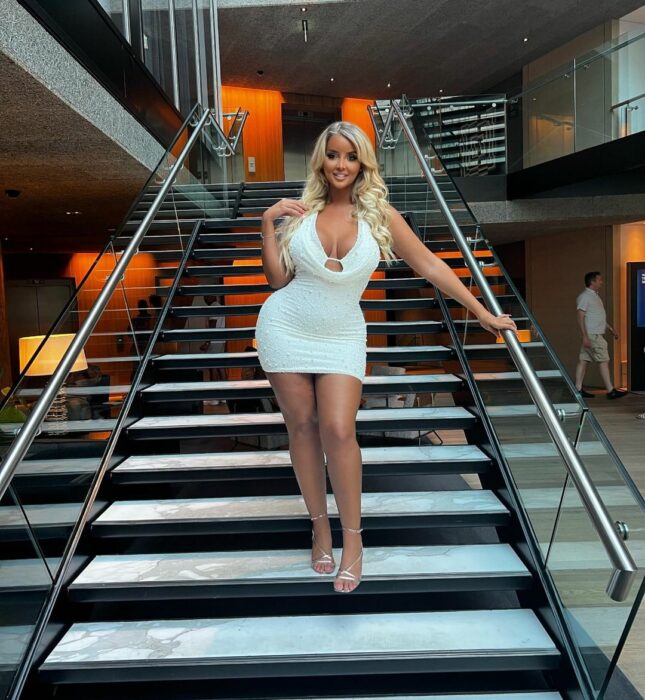 Mia costello con vestido blanco en unas escaleras