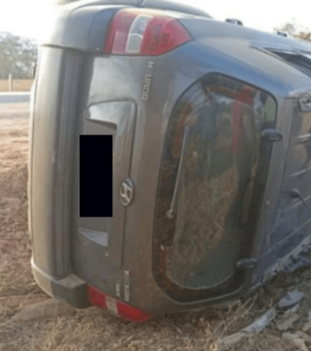 una camioneta gris volcada a un lado de la carretera