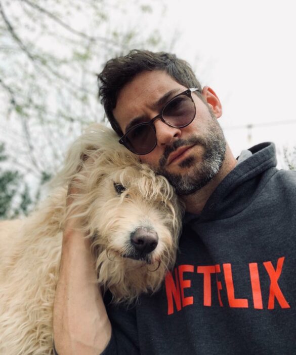 Tom Ellis abrazando a un perro junto a su cuerpo 