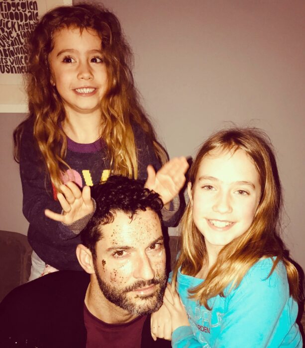 Tom Ellis posando al lado de dos niñas 