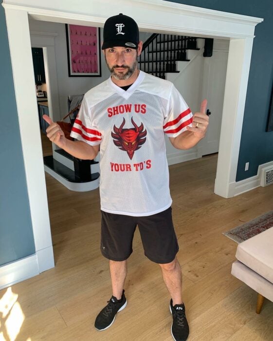 Tom Ellis posando en una casa con una camisa deportiva 