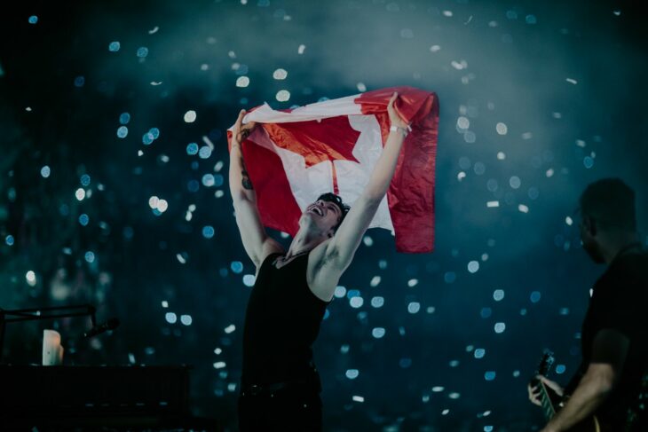 Shawn Mendes en un concierto elevando una bandera de Canadá en un concierto 