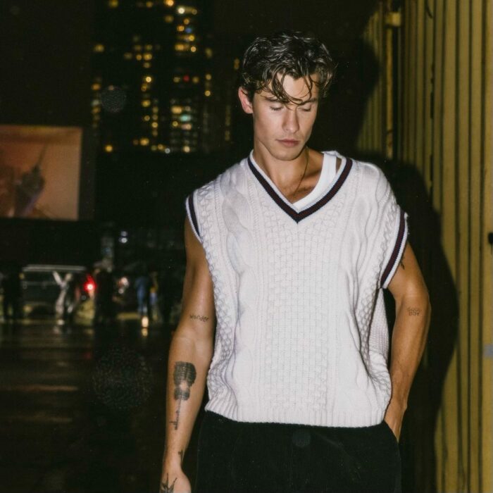 Shawn Mendes posando en una calle con un chaleco en color blanco 