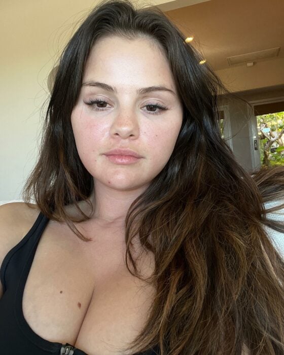 Selfie photo of Selena Gomez wearing a black blouse without makeup and with her hair down 