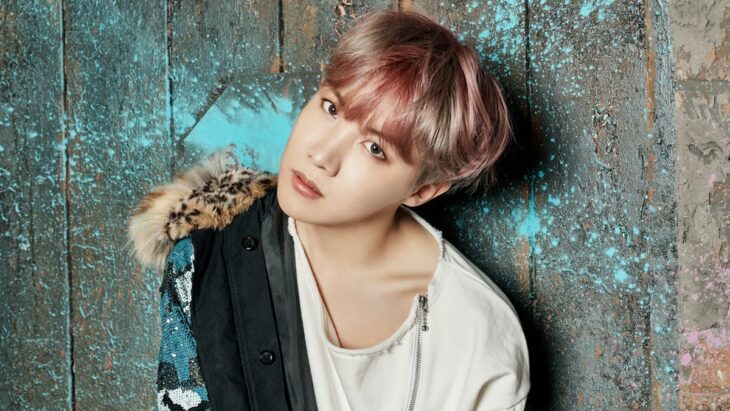 J-Hope con cabello teñido posando para foto recargado en la pared 