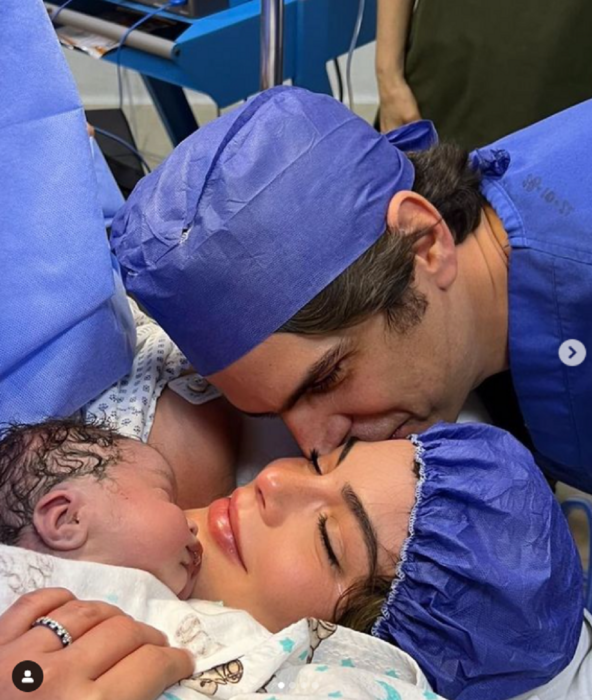 imagen del nacimiento del segundo hijo de Ximena Navarrete y Juan Carlos Valladares él la besa en la mejilla mientras ella sostiene a su hijo en su pecho llevan ropa de hospital