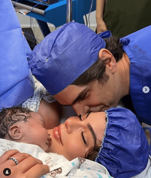 image of the birth of the second child of Ximena Navarrete and Juan Carlos Valladares he kisses her on the cheek while she holds her son on her chest they wear hospital clothes