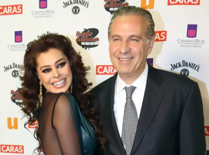 Yadhira Carrillo y Juan Collado posan en la alfombra roja de un evento del espectáculo ambos visten formal y en colores oscuros