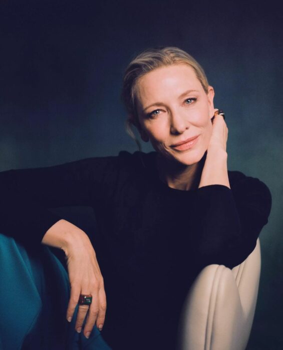 Cate Blanchet sitting in an armchair against a dark background