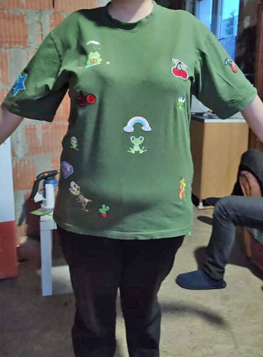 cuerpo de una mujer mostrando una playera verde con estampados de dibujos 