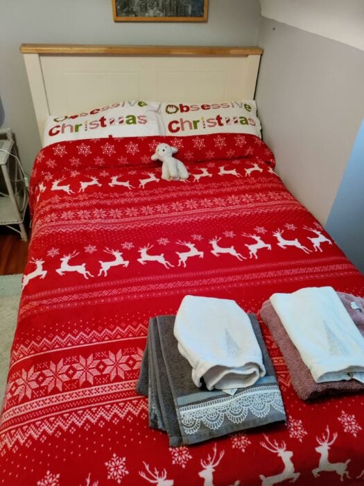 imagen de una cama adornada de navidad con un borrego en el área de las almohadas 