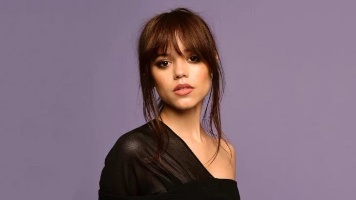 Jenna Ortega posa sexy con un vestido negro con el cabello recogido y semi despeinado 