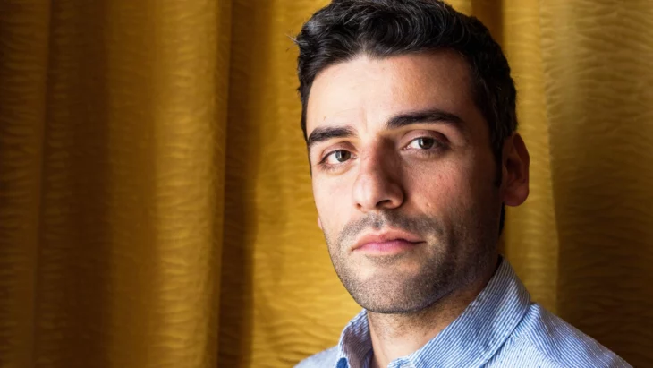 Oscar Isaac mira fijamente a la cámara lleva barba y bigote apenas visible