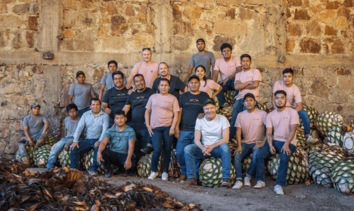 comunidad de Oaxaca México que produce el mezcal Dos Hombres los acompañan los actores Bryan Cranston y Aaron Paul algunos están sentados sobre la planta de Maguey 