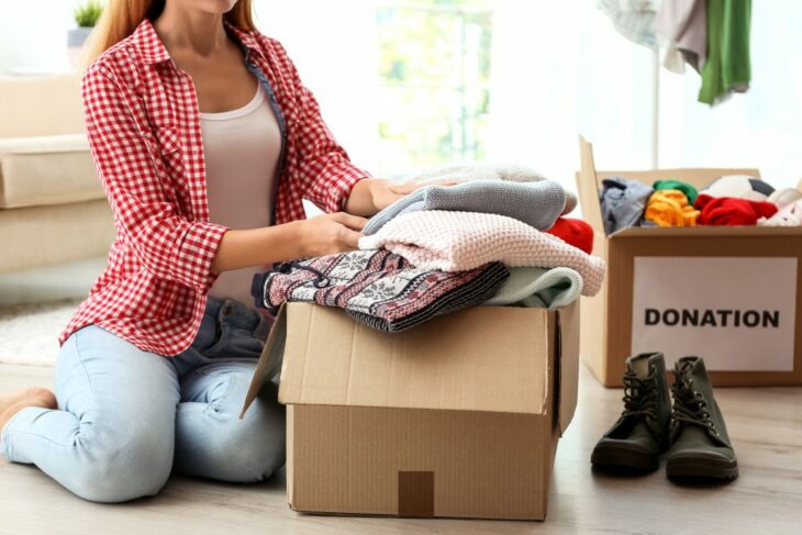 mujer metiendo ropa a unas cajas para donación 