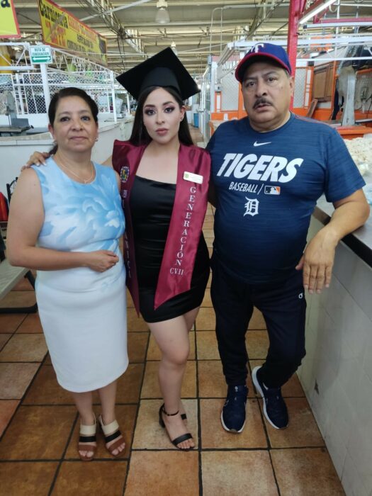 Fotografía de una chica graduada en medio de sus papás en un local en el mercado en la ciudad de Saltillo Coahuila 