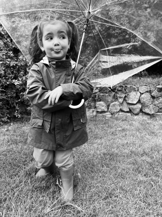 Fotografía a blanco y negro de una niña pequeña sosteniendo una sombrilla 