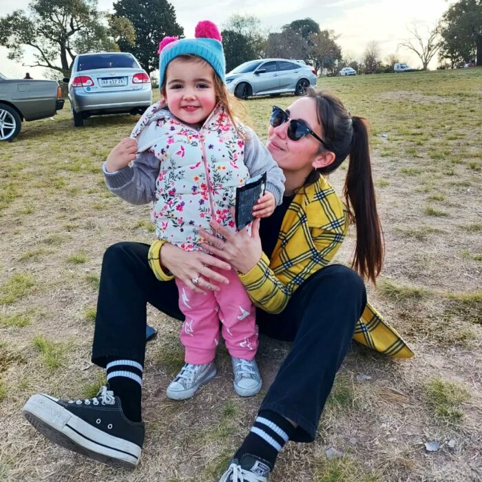 fotografía de una mujer sentada en el suelo abrazando a su hija pequeña 