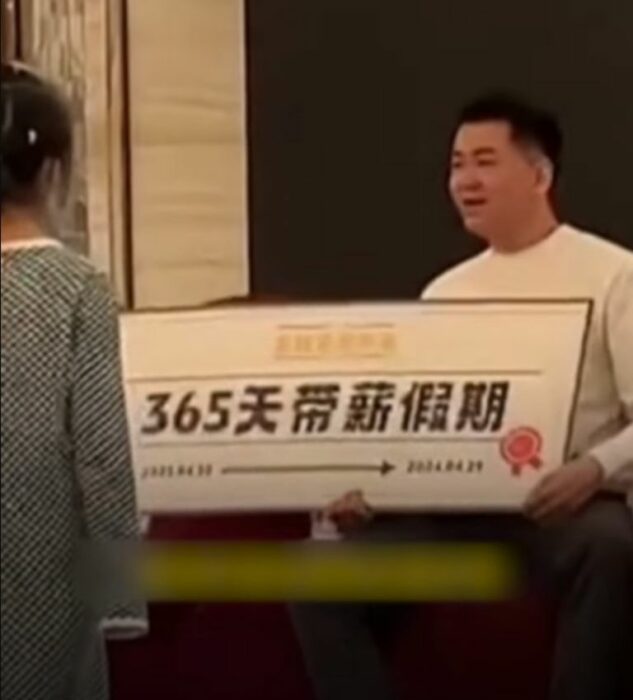 un hombre con rasgos orientales sostiene un cartel con unas palabras escritas en chino frente a él está una niña con vestido blanco y negro