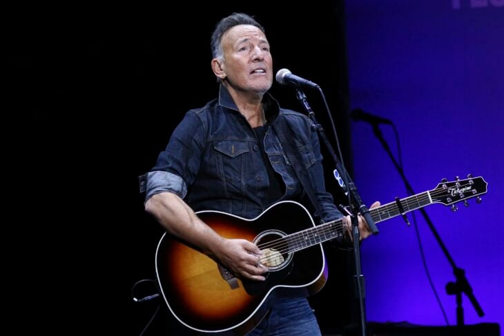 Bruce Springsteen tocando la guitarra arriba de un escenario en uno de sus conciertos 