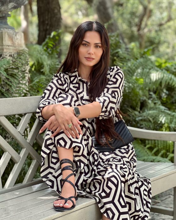 Andrea Meza posando sentada en la banca alrededor de un Jardín con plantas 