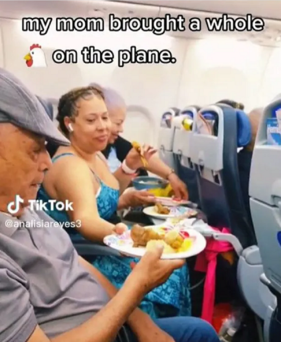 una mujer reparte a un hombre mayor un plato con alimentos en un avión están sentados en la misma fila