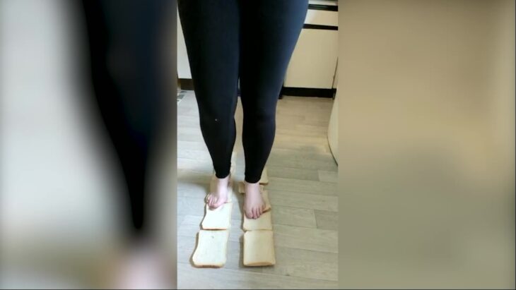 imagen de los pies de una mujer pisando piezas de pan en el suelo 