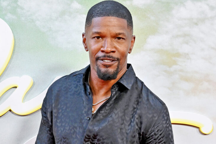 el actor Jamie Foxx sonriendo a la cámara lleva una camisa de seda de color oscuro