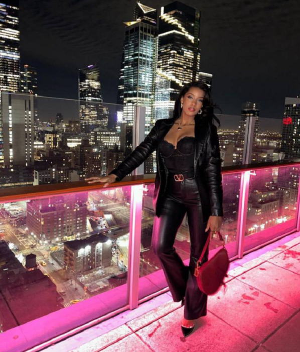 una mujer posa en la terraza de un hotel de Nueva York es de noche y las luces de los edificios están encendidas