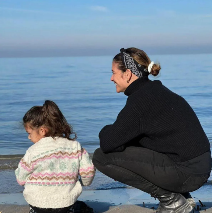 la cantante Natalia Jiménez junto a su pequeña hija a la orilla del mar ambas llevan suéteres y están un poco de espaldas a la cámara 