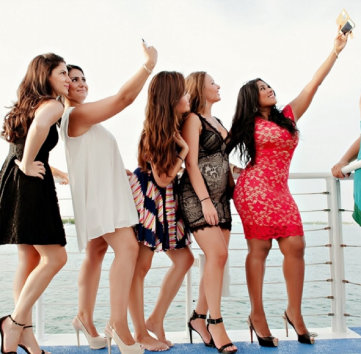 invitadas a una fiesta se toman selfies con su celular están en la cubierta de un barco