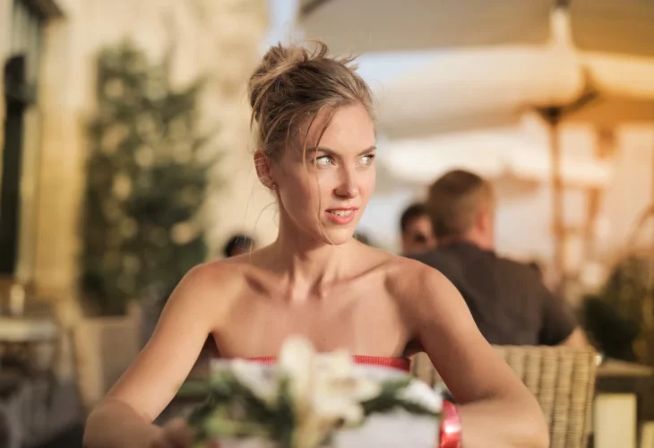 una invitada a una boda se muestra preocupada porque está sola sentada en una mesa