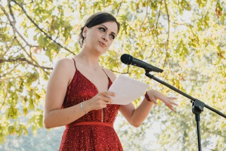 una chica habla por un micrófono en su base como invitada en un evento