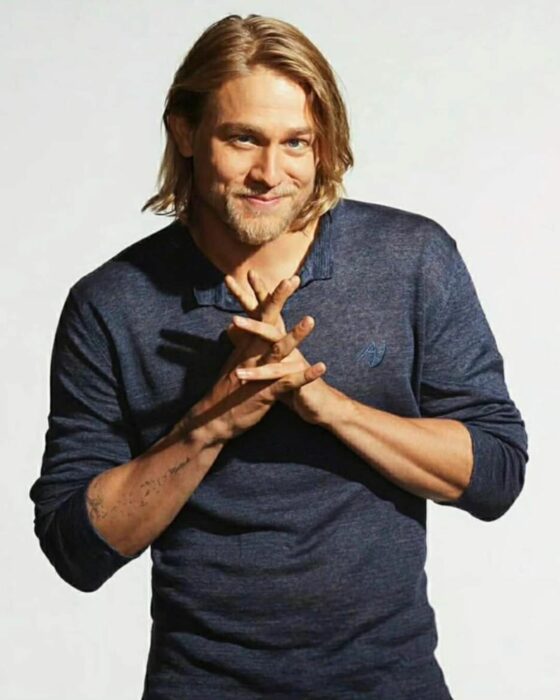 Charlie Hunnam con playera azul de manga larga y cabello largo 