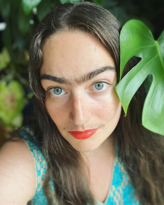 eldina posando vestida de verde al lado de plantas 