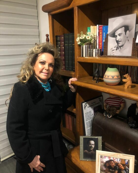 Lupita Infante Torrentera al lado de un librero con fotos de Pedro Infante 