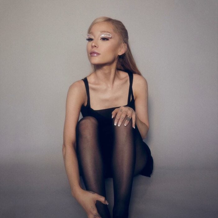 Ariana Grande sentada en el suelo con medias y vestido negro