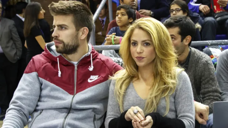 Shakira y Piqué sentados en las gradas viendo un evento deportivo ambos lucen ropa deportiva