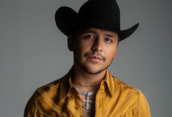 el cantante Christian Nodal posa para la cámara con texana y camisa amarilla