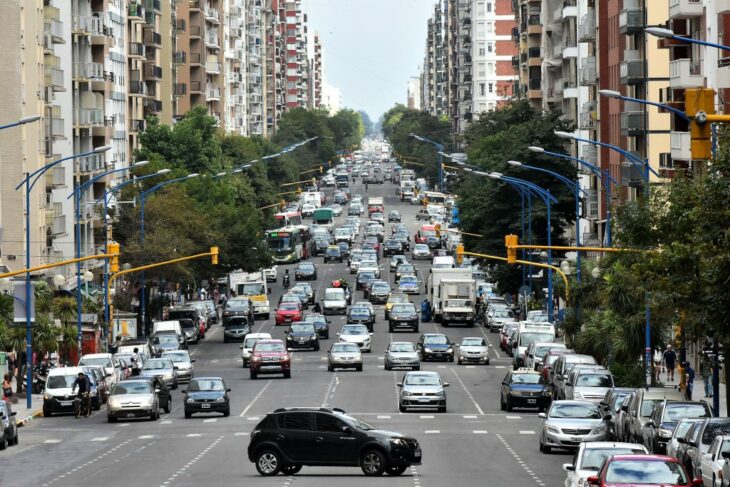 una avenida transitada con muchos autos alrededor se ven distintos edificios