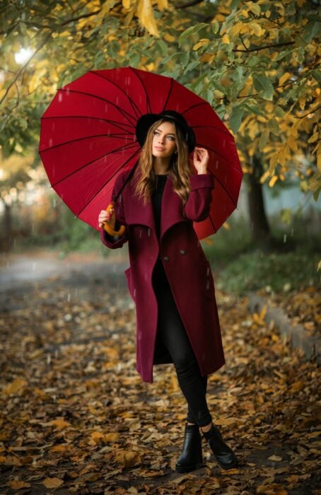 una chica con sombrilla en un jardín en otoño