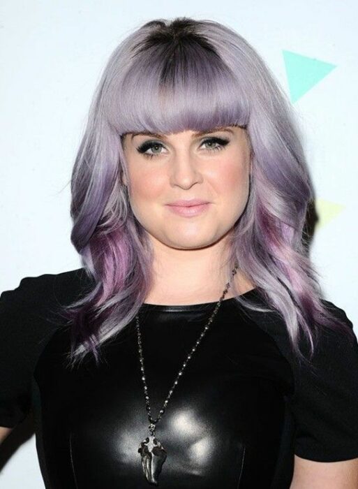 cantante Kelly Osbourne posando con un look lavender gray en una alfombra roja 