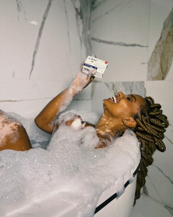 Mujer dentro de una tina tomando una ducha con jabón Dove 
