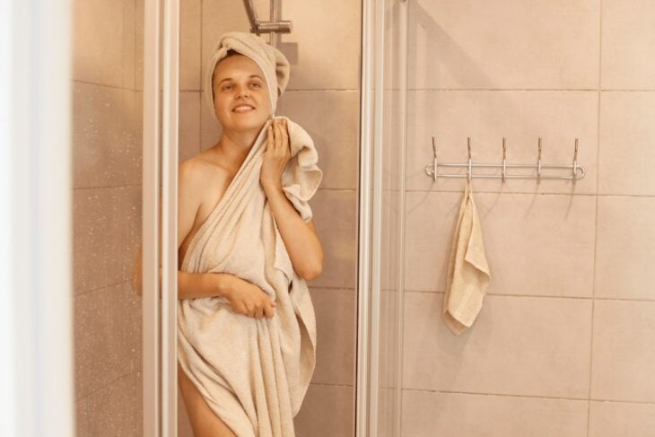 mujer saliendo de la ducha secándose con una toalla 