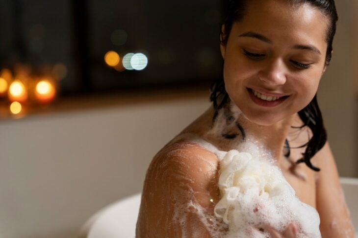 Chica en la ducha tallando su cuerpo con jabón 