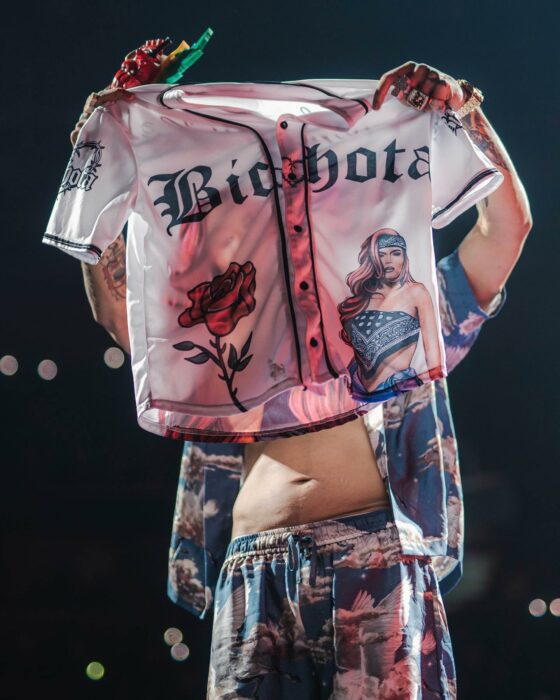 Anuel AA mostrando al público una camisa con la palabra bichota acompañado de una rosa y la imagen de Karol G 