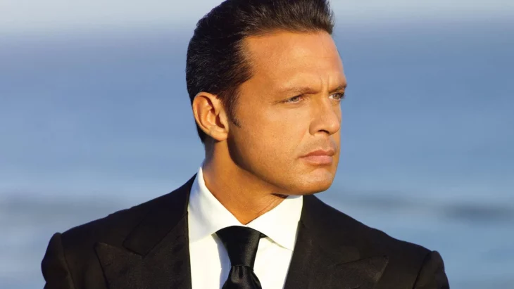 Luis Miguel posando con un traje y corbata negros combinados con camisa blanca mirando al horizonte