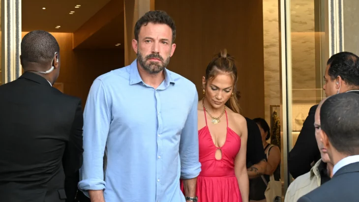 Ben Affleck y Jennifer López caminan de la mano al salir de algún lugar los acompañan personal de seguridad 