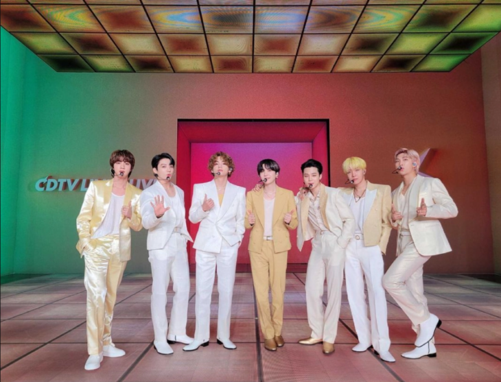 BTS posando en un estudio de televisión vestidos con colores claros